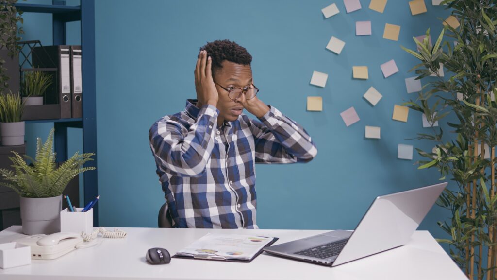 Amazed worker doing three wise monkeys symbol at desk