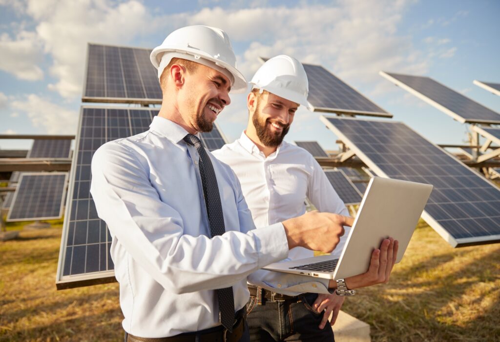 Engineer using laptop near photovoltaic panels producing renewable solar energy